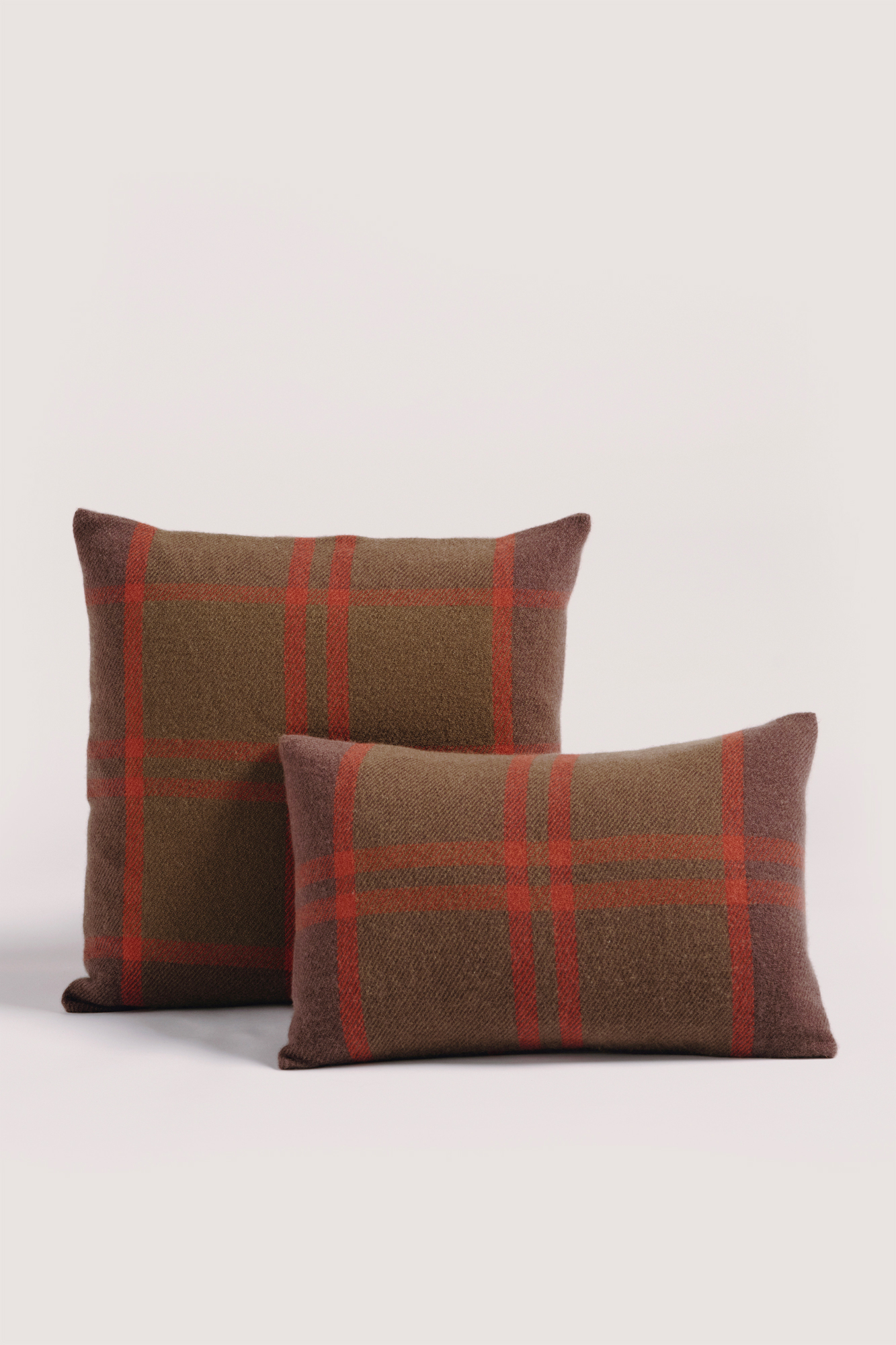 ASPEN cushion cover in Italian cashmere with green and orange checkered pattern. Cojín de cashmere italiano tejido en telar manual de forma exquisita de cuadros en tonos marrones, anaranjados y verdosos