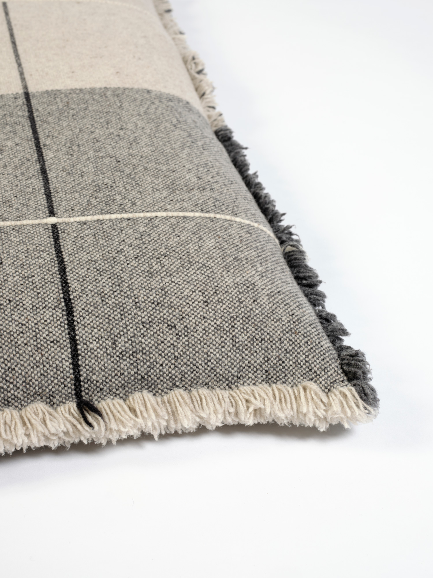 Cojín de suelo en lana merino en cuadros grises oscuros y claros