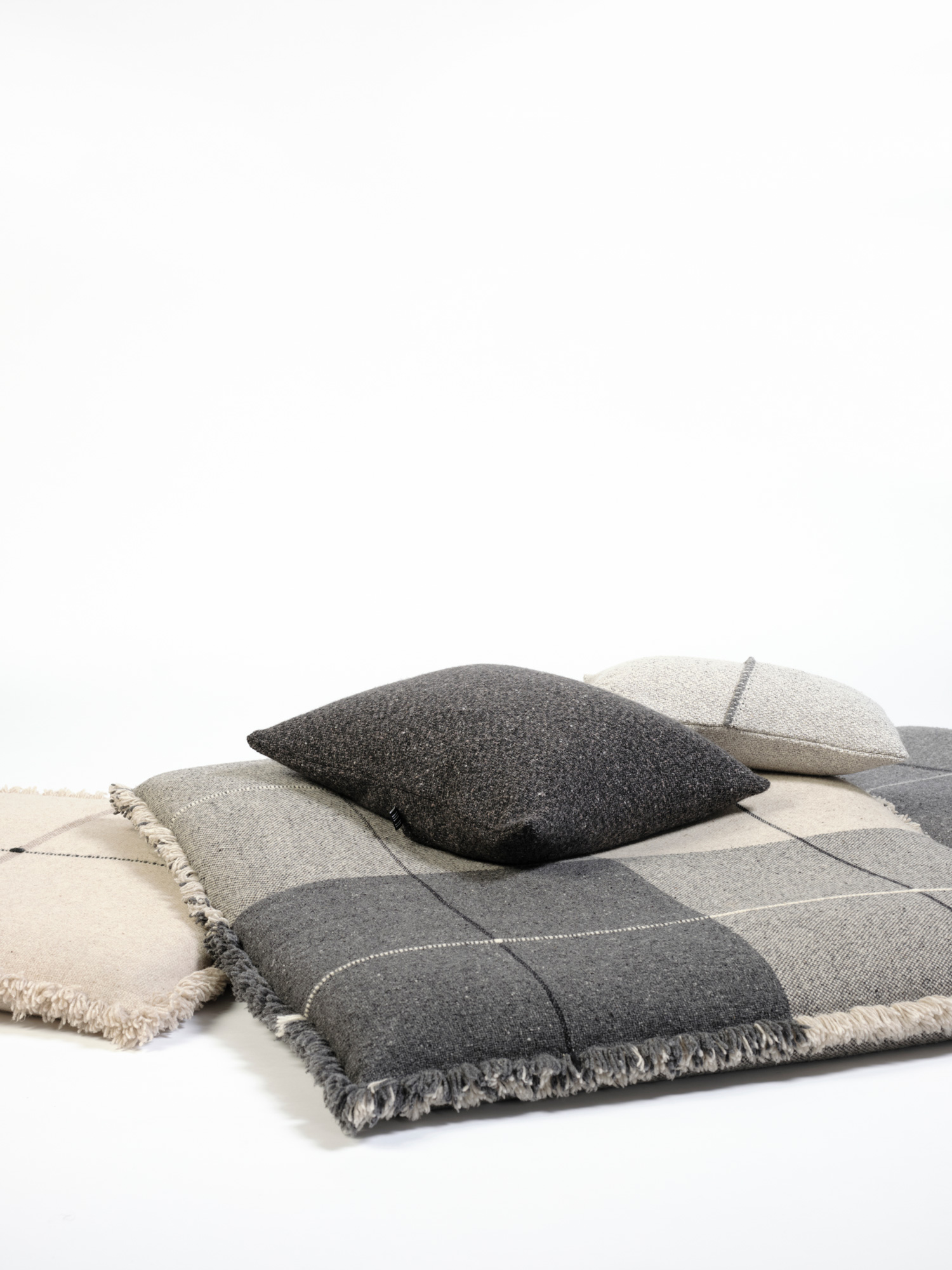 Cojines de suelo en lana merino en cuadros grises oscuros y claros