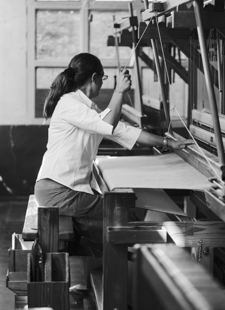Mujer tejiendo en el taller de Teixidors en telar manual de madera