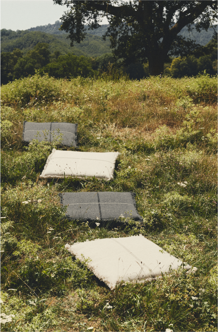 Cuatro cojines Teixidors de suelo en varios colores expuestos sobre una pradera