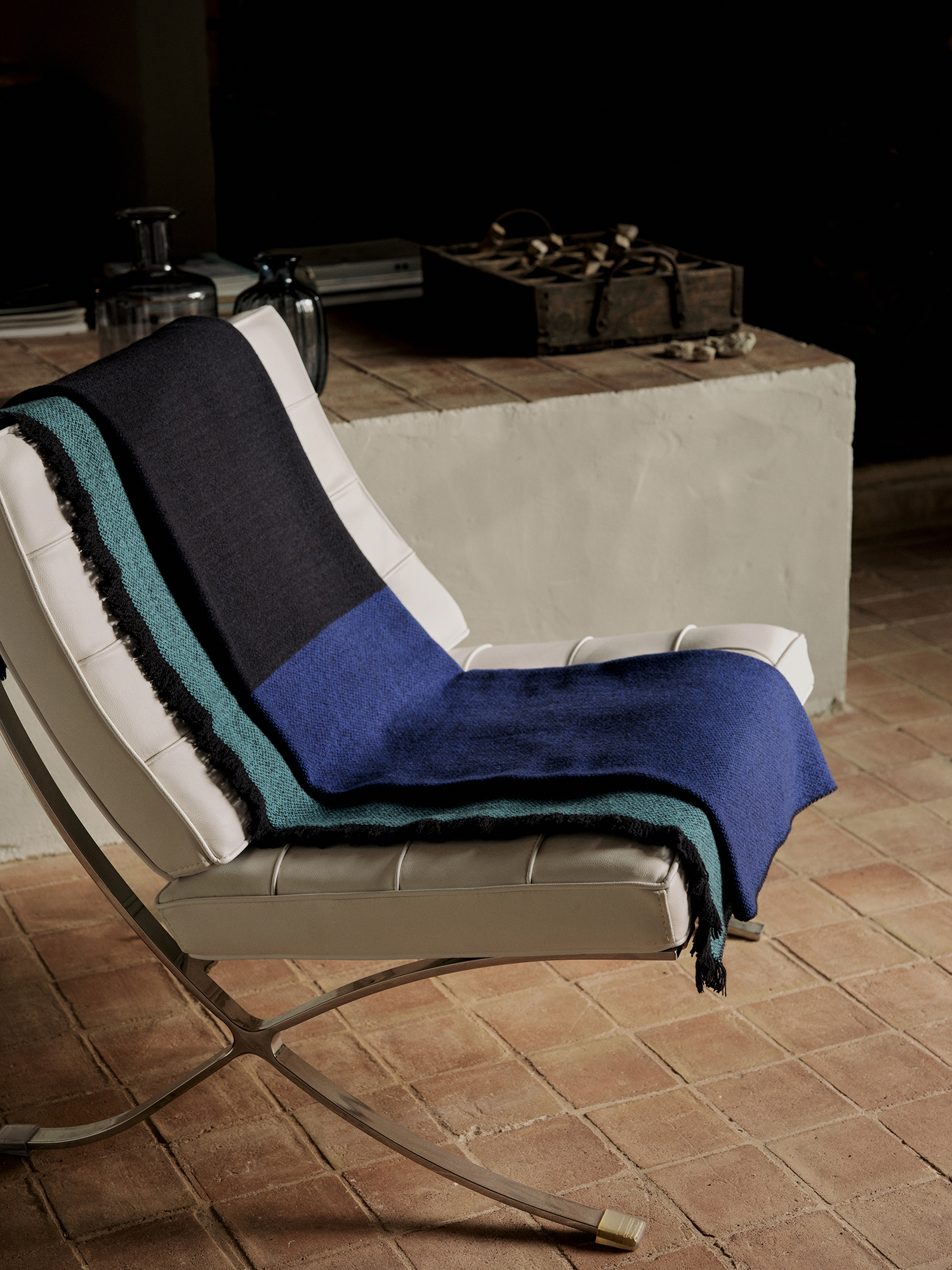 Manta de diseño en lana merino color azul marino y azul chillón sobre silla de diseño en piel blanca
