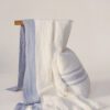 Bodegon Manta cama y cojines Eunoia franjas azules sobre lino blanco europeo