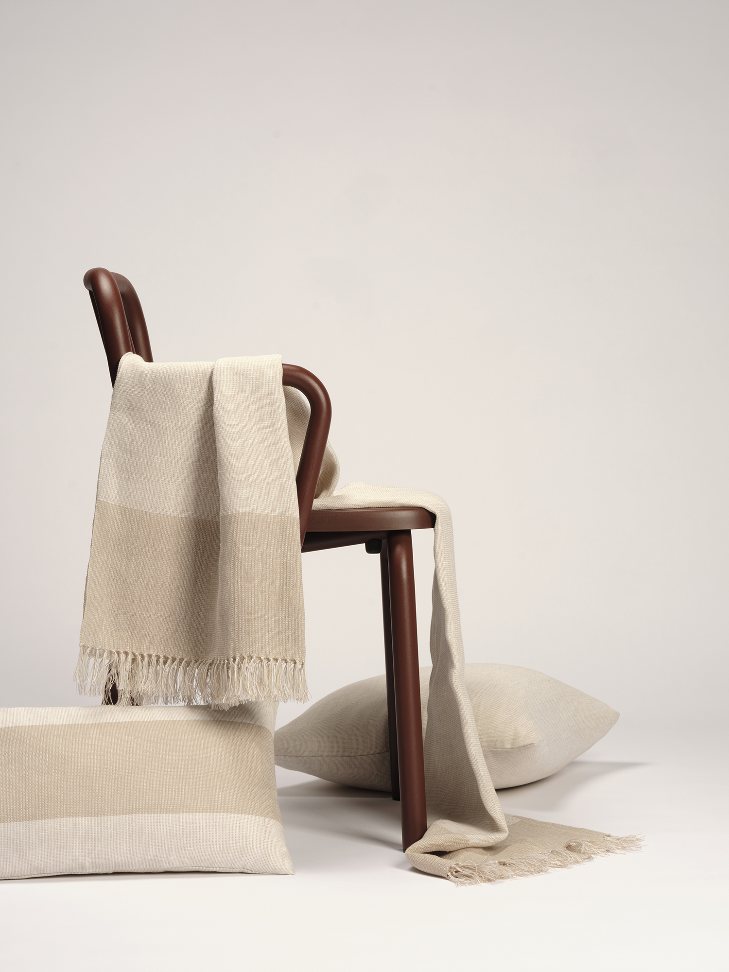 Manta y cojines de lino europeo en tonos grises sobre silla de Muebles de 114