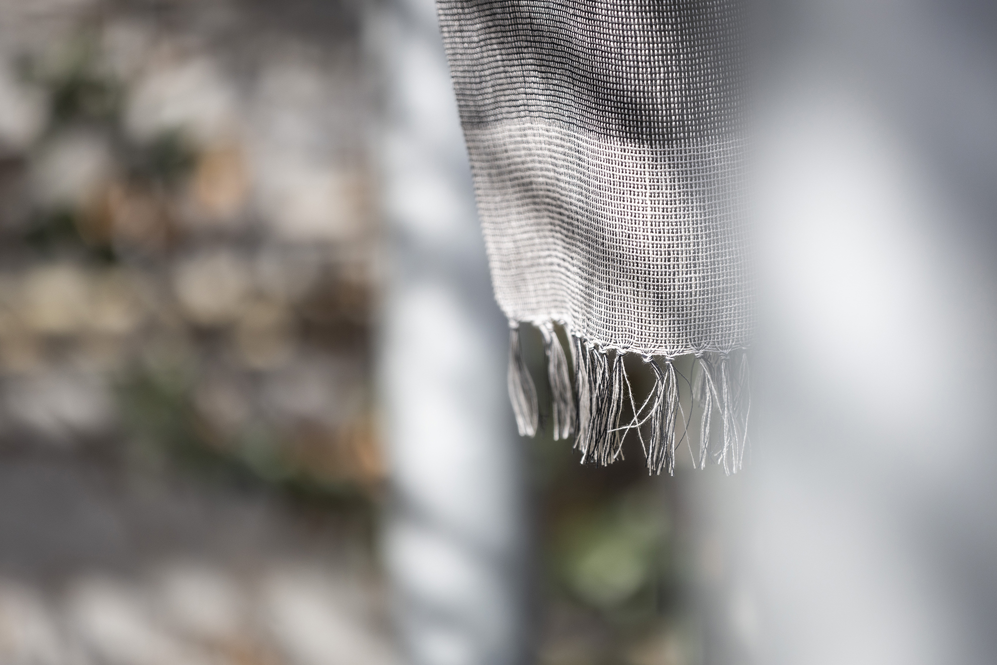 Detalle de flecos de manta de lino europeo en tonos grises 