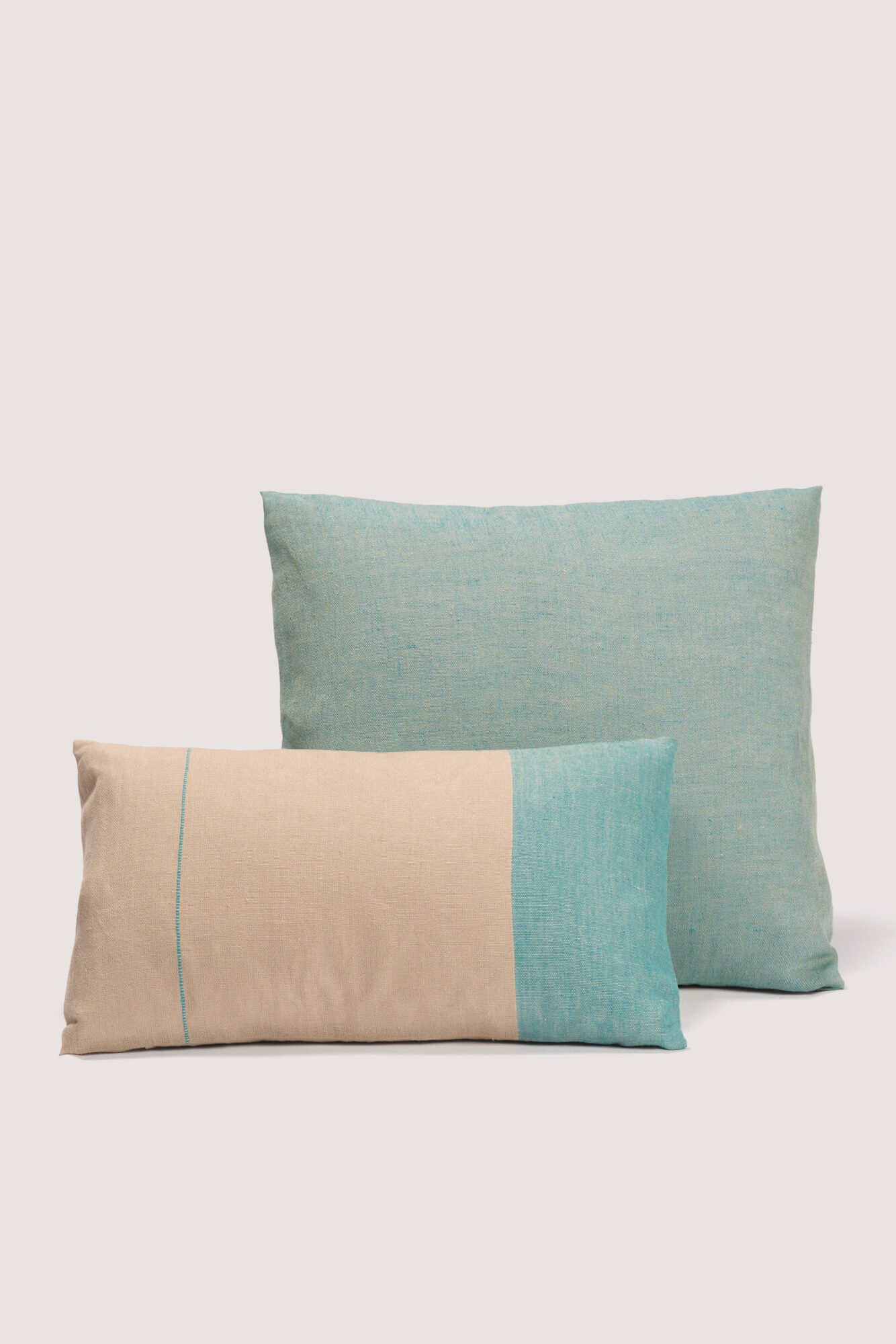 Emuna a cushion cover in 100% certified European linen, a timeless classic blending natural colors and vibrant tones inspired by the Mediterranean. Una funda de cojín artesanal de lino europeo certificado en tonos turquesas inspirado en el mediterraneo