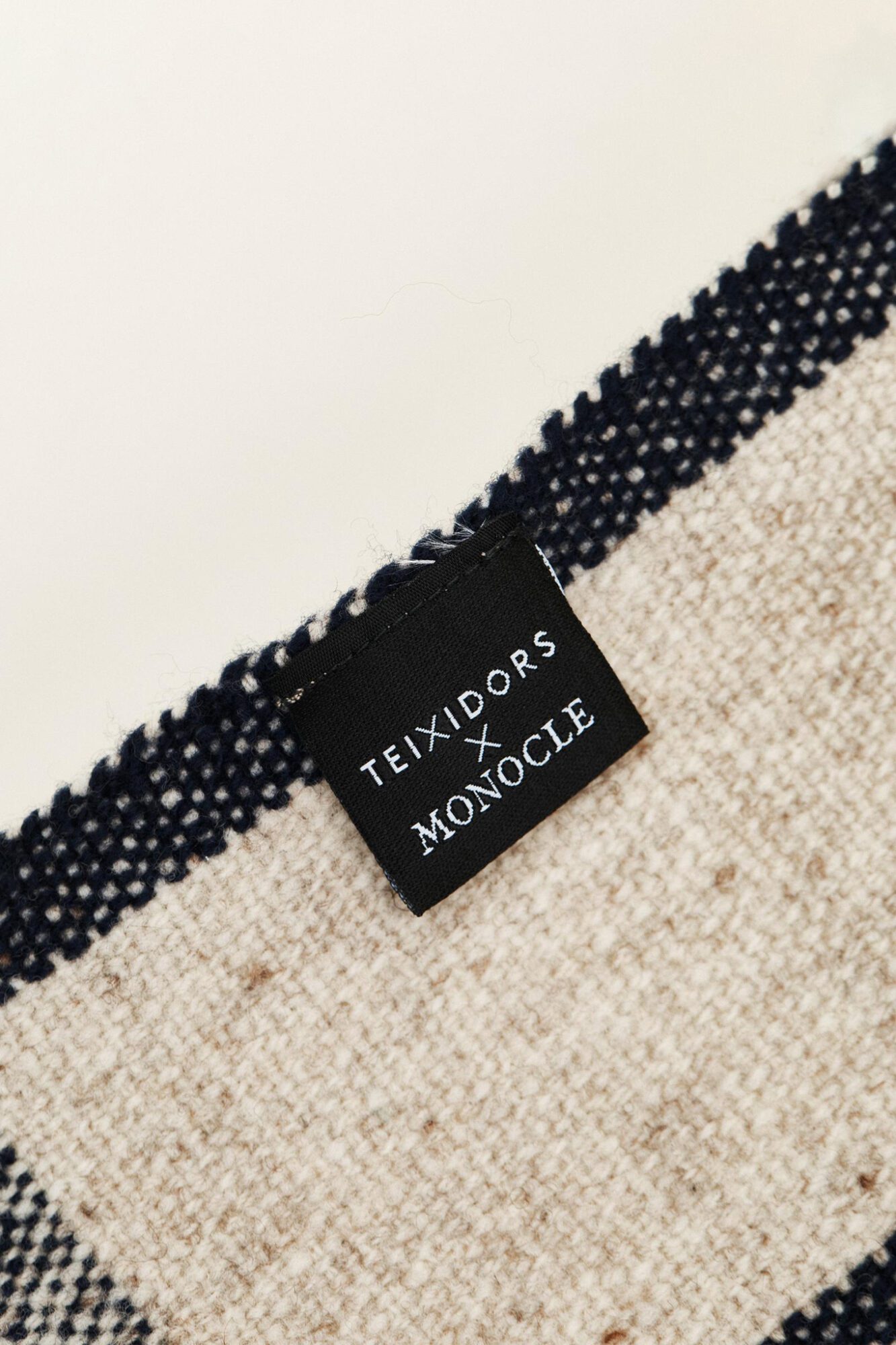 Colaboración Teixidors x Monocle plaid de lana merino detalle de etiquetado especial de colaboración
